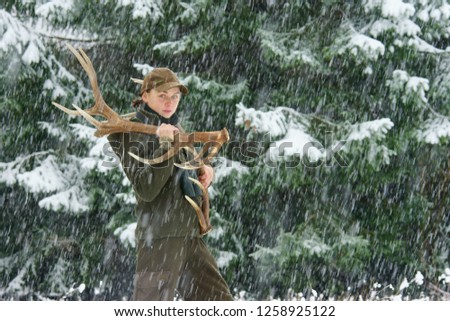 A lucky beautiful woman carries deer antler sheds through a winter forest