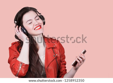 beautiful woman listening to music on headphones on the phone. Color of the year 2019 living coral. banner