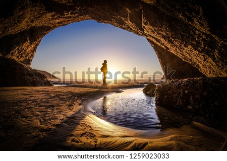 Young man stands at a cave exit. A person deep thinking at the exit of a cave. Beautiful landscape formation of a cave in New Zealand Royalty-Free Stock Photo #1259023033