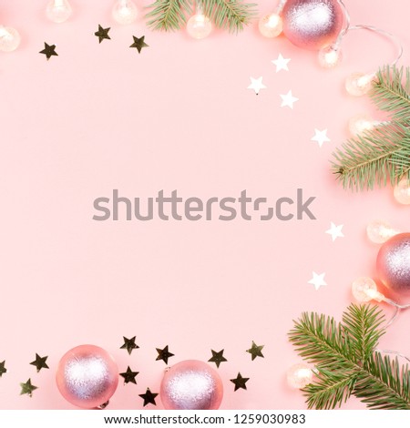 Christmas background with fir branches, lights, pink decorations on pink