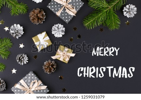 Merry Christmas and Happy New Year greeting card with fir branches, presents, decorations on black