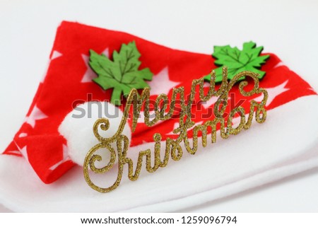 Merry Christmas written with golden letters covered in glittter and red and white Christmas hat
