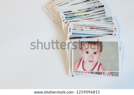 Pile of printed photographs in disorder on a white background. Picture of the baby on the top.