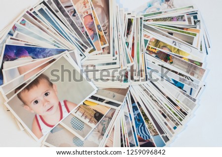Pile of printed photographs in disorder on a white background. Picture of the baby on the top.