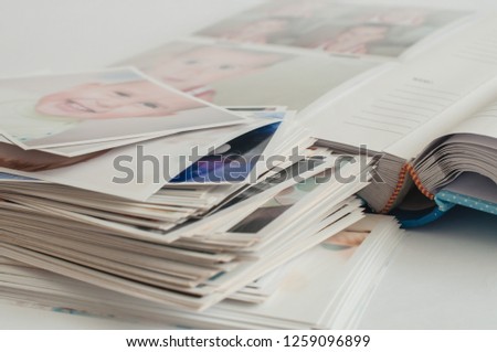 Photo album and pile of printed photographs on a white background. Pictures of baby.