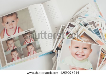 Pile of printed photographs in disorder on a photo album with pictures.