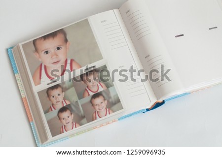 Printed photographs in a photo album lying on a white background. Pictures of the baby.