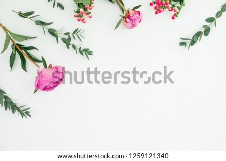 Floral frame of pink peonies, hypericum and eucalyptus branches on white background. Flat lay, top view