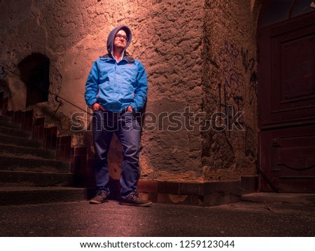 Young man standing at dark city site with light from top