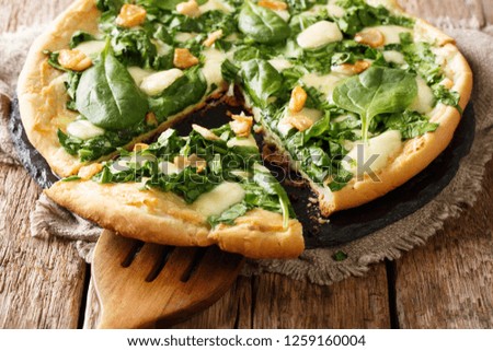 Italian pizza with spinach, garlic and ricotta cheese and mozzarella and white sauce close-up on the table. horizontal

