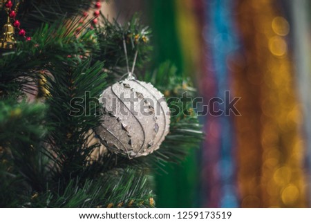 White decorative ball on the christmas tree on glitter bokeh background with blurred colorful background. Merry christmas card. Winter xmas theme. Happy New Year.