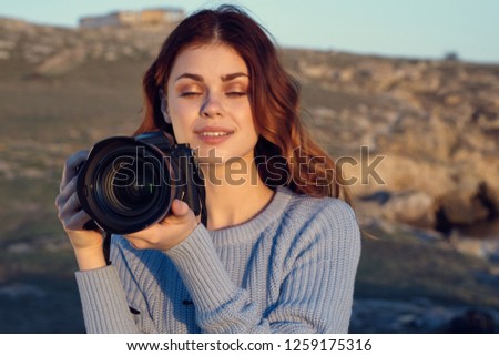 A woman with a camera is standing in nature                     