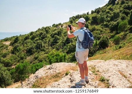 Travel man with backpack standing take a photo by smartphone Mountians Sunny day Copy space