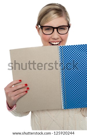 Cropped image of smiling young girl student holding note book close to her.