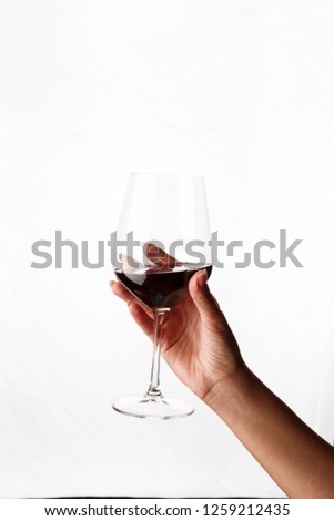 wine glass with red wine in hand on white background Royalty-Free Stock Photo #1259212435