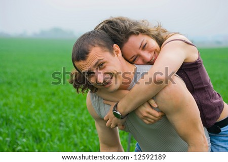 Happy young couple having fun in a grass field