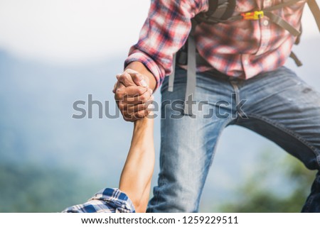 Helping hand outstretched for salvation . Strong hold. Couple hiking help each other in mountains . Two people climbing on mountain and helping. Royalty-Free Stock Photo #1259229511