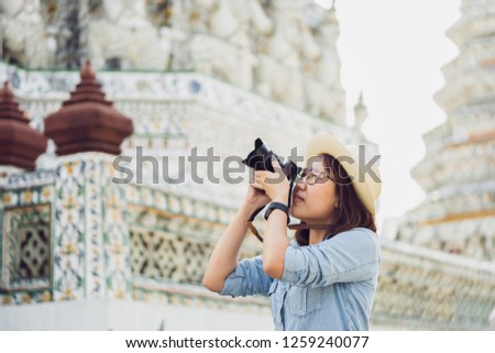 Beautiful woman tourist Held camera to capture the memories. Wat Arun Temple in Thailand. using as background  travel concept with copy spaces for your 
