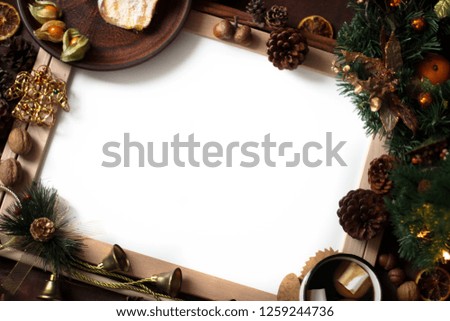 Top view of Christmas decor with copy space area. Christmas objects: dried sliced orange, cinnamon, pine cone, fir branch, cup coffee, cheesecake, walnut, golden Christmas bells