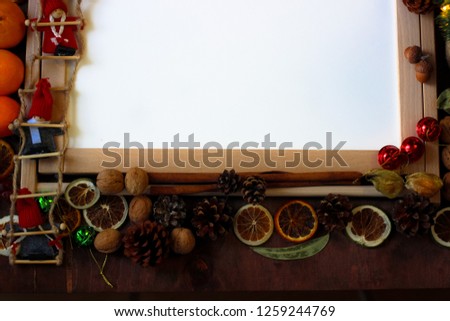 Top view of Christmas decor with copy space area. Christmas objects: dried sliced orange, mandarines, cinnamon, pine cone, fir branch, cup coffee, cheesecake, walnut, golden Christmas bells