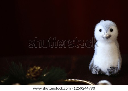 View of the Christmas decor. Christmas items: penguin toy, fir tree branch, blurred dark background. Copy space text area.