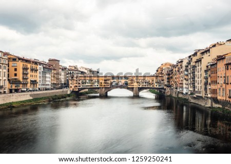 Travel photo of Ponte Vecchio bridge over the Arno River in Florence Italiy. Colorful buildings on a cloudy day. 