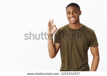 Charismatic and attractive african american guy saying okay and no worries showing ok or perfect gesture smiling confident. assertive having business under control posing self-assured over grey wall