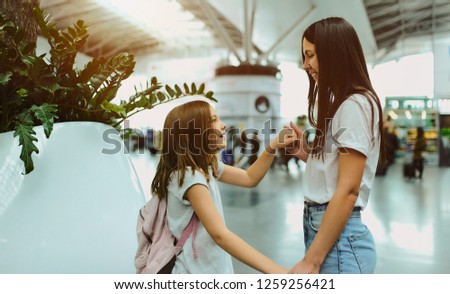 Mom and daughter at the airport. Holding hands, laughing.