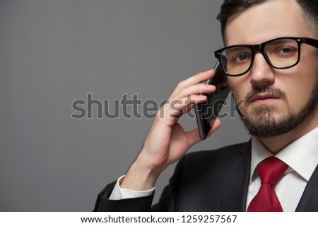 Serious thoughtful businessman with glasses and formal suit Talking by smartphone. Place for text