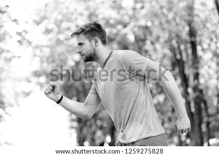 Moving to his goal. Man confident young running in park, side view. Sportsman ambitiously moves to achieve sport goal. Masculinity and sport achievements concept. Guy concentrated runs for his goal.