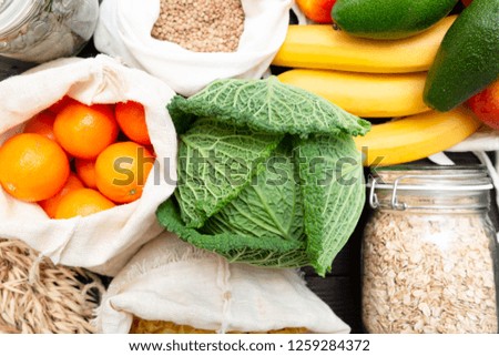 Zero waste grocery shopping. Package-free food on dark wooden table with texture. Fresh vegetables and fruits in Eco cotton bags. Plastic-free package