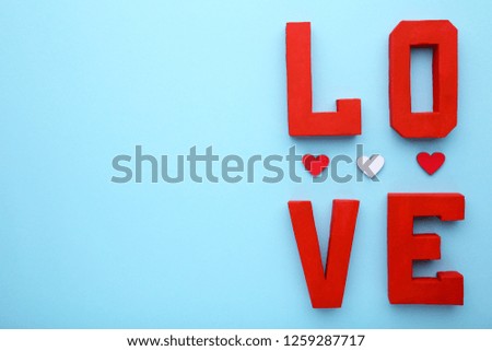 Red letters love with wooden hearts on blue background. LOVE word on blue.