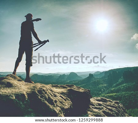 Photographer taking pictures with SLR camera at midday. Nature landscape photographer with telephoto lens. Silhouette of tall man