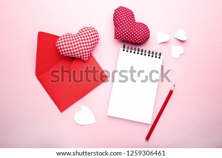 Fabric hearts with envelope, notebook and pencil on pink background