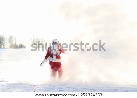 Santa in the winter field. Santa magical fog walking along the field. Santa on Christmas Eve is carrying presents to children in a red bag
