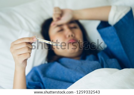 Asian Beautiful Woman Hypothermia has been measured by fever. Lie on the bed to give a body of rehabilitation. The concept of medical care to patients at home by yourself. Royalty-Free Stock Photo #1259332543
