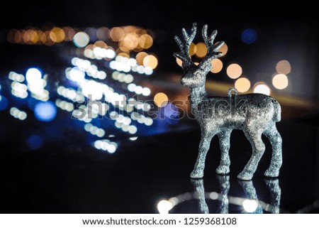 Christmas deer on the table by the window in the evening against the background of the night city with bokeh