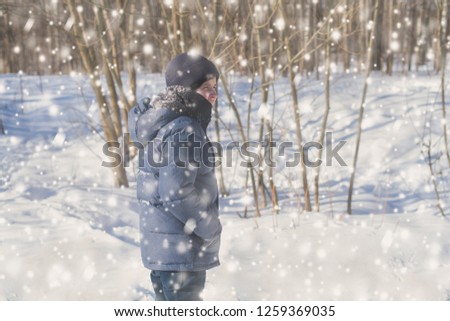Teen boy in the park in the winter snowfall.