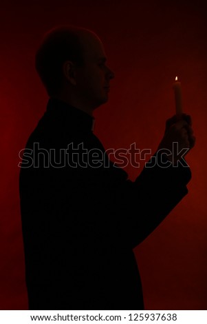 Portrait of young Pastor holding candle in his hand, isolated on black