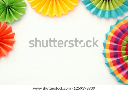 Festive and party background with colorful paper circle fans over wooden white background. Copy space