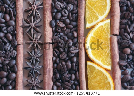 Coffee beans background with pieces of orange, anise star and cinnamon sticks.