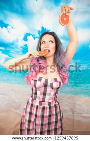 beautiful girl with Ombre hair is pink checkered summer dress with slices of grapefruit