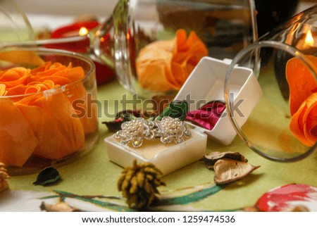 Romantic composition with wine glass, roses, jewelry, candles and bottle of wine. Candle light and dry leaves of flower on the table.