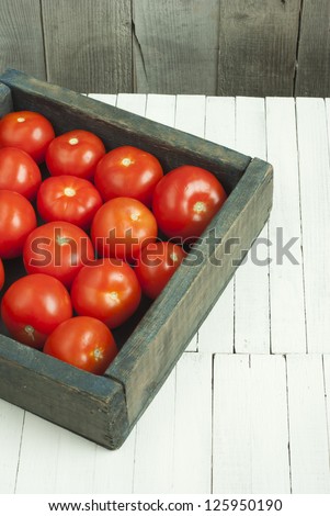  tomatoes in rustic wooden box, white wood table
