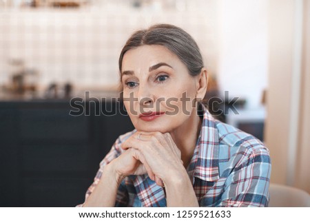People, aging, maturity and life perception. Picture of neat pensive senior elderly young European female with healthy shiny skin and colored hair holding hands under her chin and daydreaming