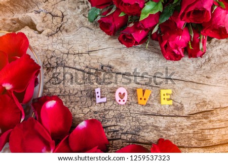 Red roses with word 'LOVE' on old wooden background with copy space,  