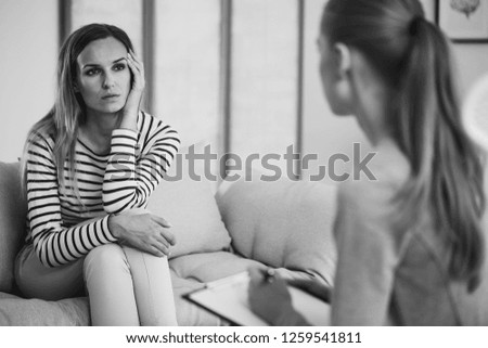 Black and white photo of worried woman consulting her therapist during session in office