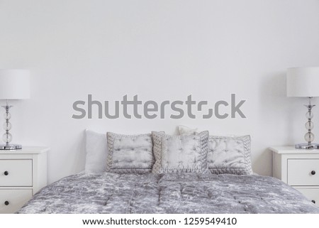 Closeup of velvet grey duvet and pillows on comfortable bed, real photo with copy space on empty white wall