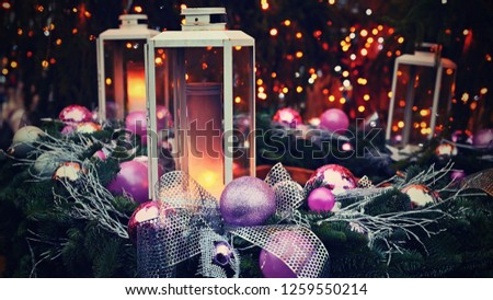Christmas background. Lanterns with purple ornaments on a Christmas tree. Beautiful blurred abstract colorful lights in the background. Concept for holidays, winter time and a happy new year.