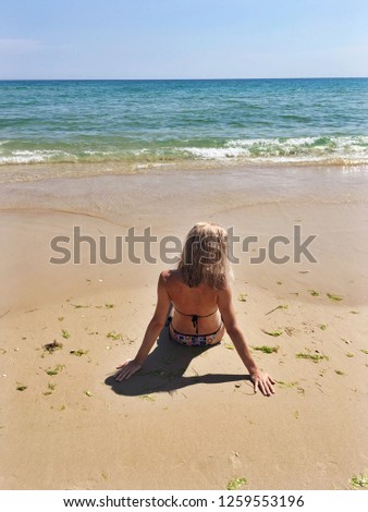 Girl blonde on the beach. The girl blonde sits on the sand on the shores of the Atlantic Ocean.